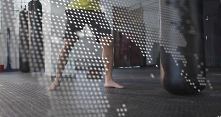 Holding man in green shirt performing fighting stance in gym, with punching bag, world map overlay