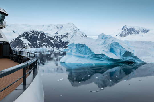 Antarctic Seascape at Neko Harbor with Iceberg and Mountains, Photographed from Expedition Cruise Ship with Railing Visible.