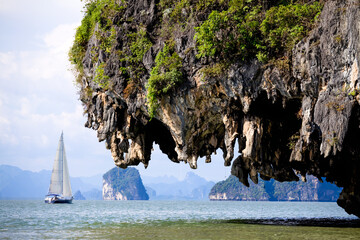Sailboat sailing through Phang Nga Bay near Phuket, Thailand on a sunny day.