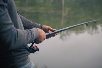Fisherman holding a fishing rod on a background of a lake