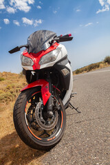 Obraz premium Rear view of a black and red motorcycle on the road.
