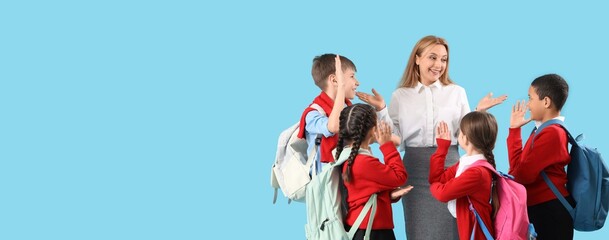 Mature female teacher and little students on blue background with space for text