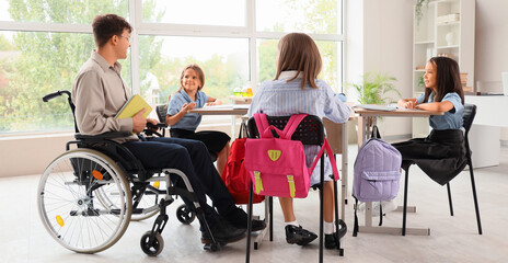 Male teacher in wheelchair conducting lesson to little pupils at school