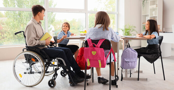 Male teacher in wheelchair conducting lesson to little pupils at school