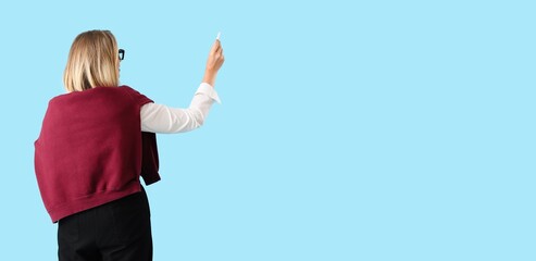 Female teacher holding chalk on blue background with space for text