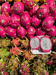 Fresh dragon fruit display at market with vibrant pink pitaya and sliced fruit
