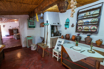 A traditional portuguese  rustic kitchen with wooden beams, clay pots, hanging garlic, and vintage tableware