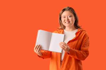 Fototapeta premium Young woman with book on orange background