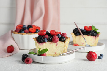 Plates with pieces of delicious berry pie on white grunge background, closeup