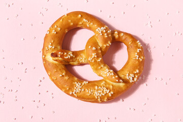 Tasty pretzel with salt on pink background, closeup