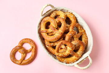 Basket with tasty pretzels on pink background, closeup