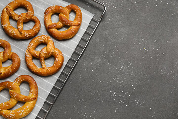 Cooling rack with tasty pretzels on black grunge background, closeup