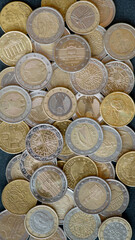 Euro coins lie in bulk on a black background, top view