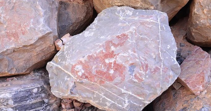 Closeup gray color jagged rock with tan and pattern of white erosion cracks in rock wall 4k