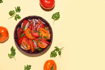 Bowl of fresh tomato salad with red onion and parsley on yellow background