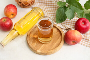 Glass and bottle of fresh apple cider with fruits on white background, closeup