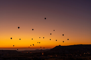 Hot air balloon flying over rocky landscape at sunrise in Cappadocia. Turkey