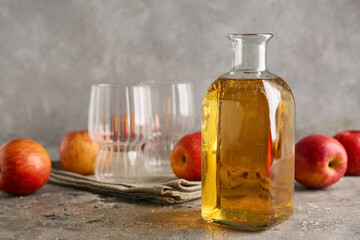 Bottle of fresh apple cider and fruits on grey background