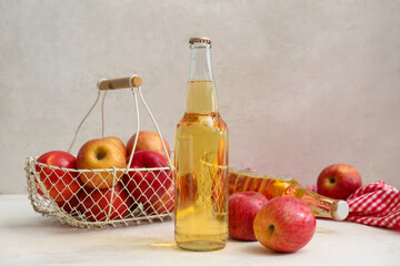 Bottles of fresh apple cider and basket with fruits on white background