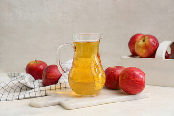 Jug of fresh apple cider and basket with fruits on white background