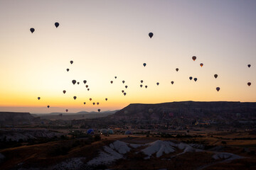 Hot air balloon flying over rocky landscape at sunrise in Cappadocia. Turkey
