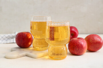 Glasses of fresh apple cider and fruits on white background