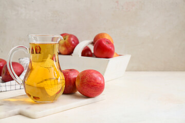 Jug of fresh apple cider and basket with fruits on white background