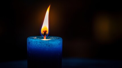 Close-up of flickering flame on blue candle in dark room