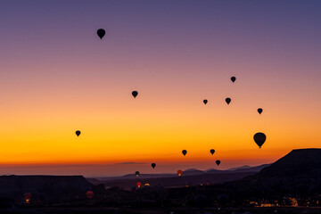 Hot air balloon flying over rocky landscape at sunrise in Cappadocia. Turkey