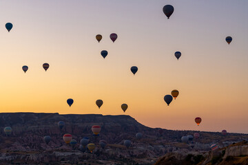 Hot air balloon flying over rocky landscape at sunrise in Cappadocia. Turkey
