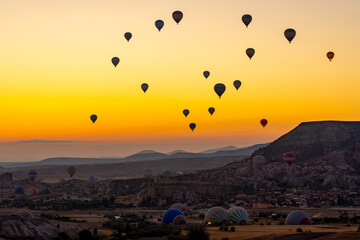 Hot air balloon flying over rocky landscape at sunrise in Cappadocia. Turkey