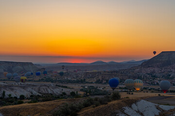 Hot air balloon flying over rocky landscape at sunrise in Cappadocia. Turkey