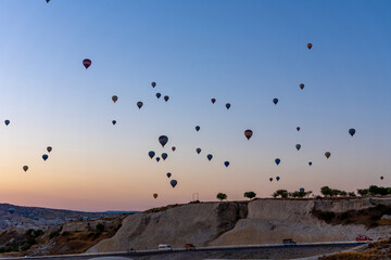 Hot air balloon flying over rocky landscape at sunrise in Cappadocia. Turkey