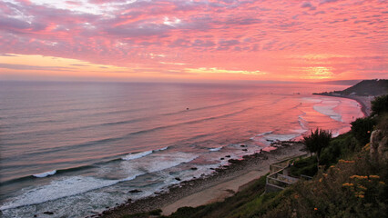Vast ocean horizon under a stunning pink sunset with gentle waves and coastal landscape