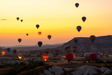 Hot air balloon flying over rocky landscape at sunrise in Cappadocia. Turkey