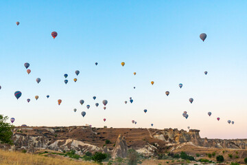 Hot air balloon flying over rocky landscape at sunrise in Cappadocia. Turkey