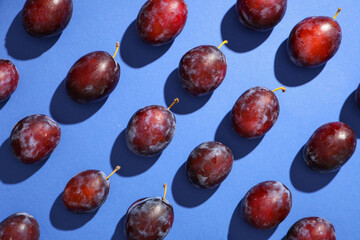 Fresh ripe plums on blue background