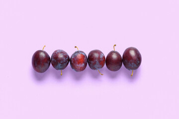 Fresh ripe plums on lilac background
