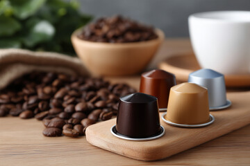 Coffee capsules and roasted beans on wooden table