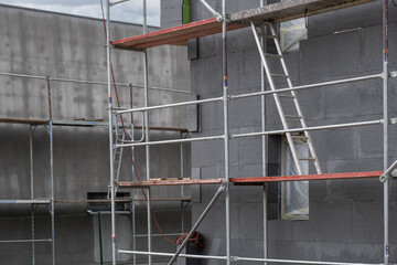 building under construction shows a facade covered in dark gray insulation panels. scaffolding.