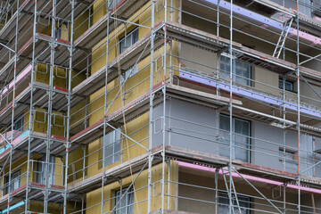 The yellow natural insulation panels exterior covered in scaffolding