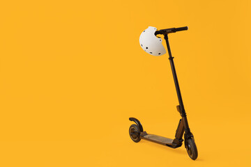 Modern electric scooter with helmet on yellow background