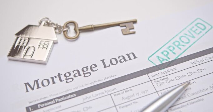 A hand stamping the word &lsquo;APPROVED&rsquo; in green ink on a mortgage loan application form, symbolizing successful home loan approval by the bank. Real video frame - genuine footage, not AI-generated.