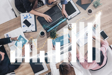 A diverse team of professionals engages in a collaborative meeting, discussing business strategies and analyzing data with digital graphs overlaying their workspace. Impute