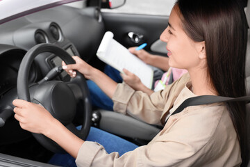 Young woman with instructor passing driving license test in car, closeup