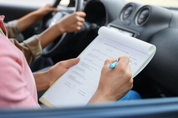 Male instructor conducting driving license test in car, closeup