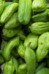 Fresh green chayote squash piled together at a local market, healthy tropical vegetable harvest