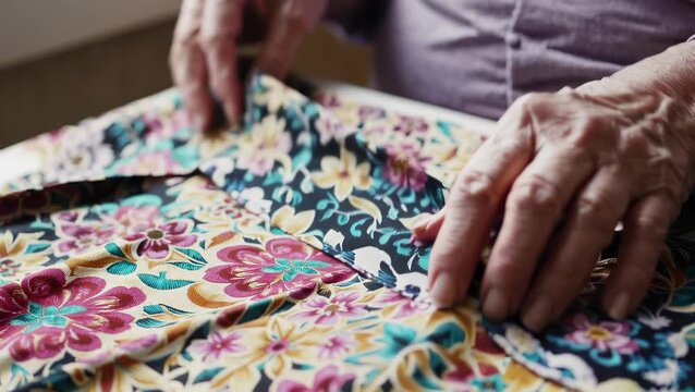 Elderly Caucasian Woman Sewing Floral Fabric Near Window with Careful Hands