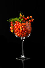 Cherry Tomatoes Overflowing in Wine Glass with Basil on Black Background