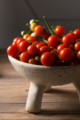 Cherry Tomatoes Arranged in Unusual Vase on Wooden Surface &ndash; Creative Food Still Life
